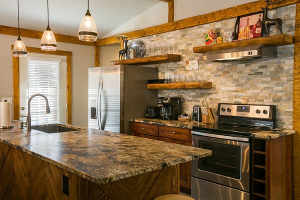 Modern kitchen with granite countertops, wooden beams, brick backsplash, stainless steel appliances, and wooden open shelving.