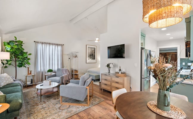 Bright, airy open-plan living and dining room with vaulted ceilings and wicker pendant lights in a Velo vacation rental